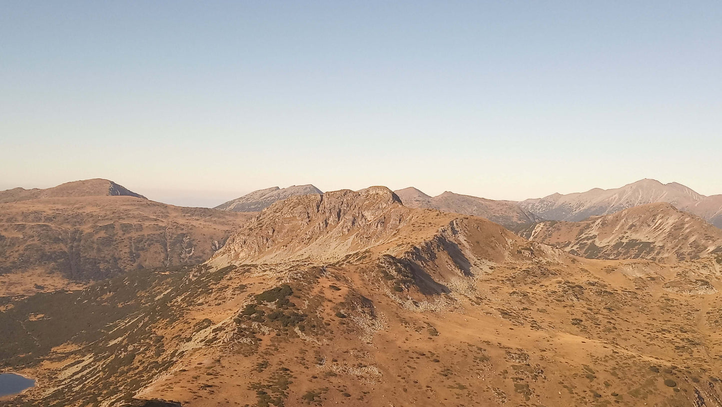 Aerial view of rocky mountains under a clear sky, showcasing natural beauty and rugged terrain.