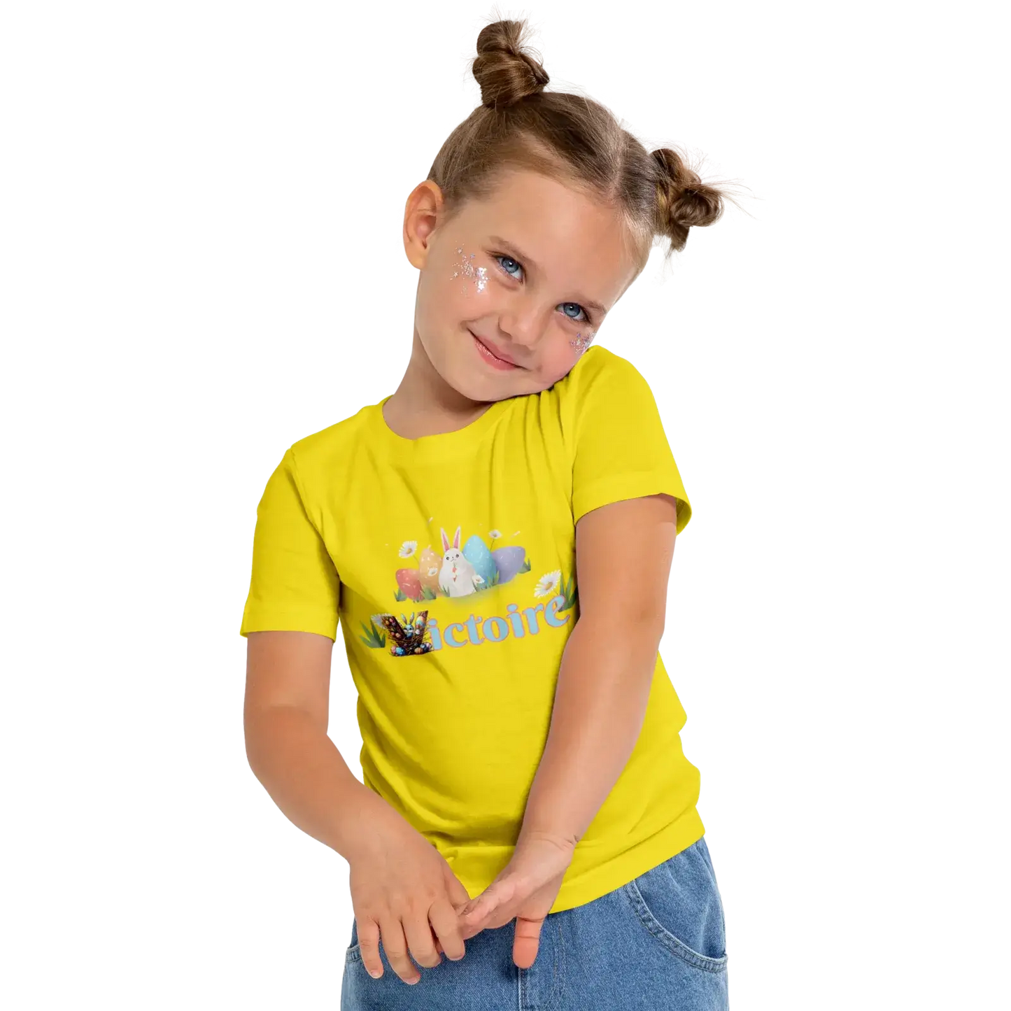 Young girl in a bright yellow t-shirt with playful graphics, smiling and posing cheerfully.