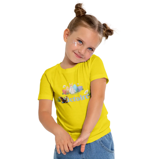 Young girl in a bright yellow t-shirt with playful graphics, smiling and posing cheerfully.