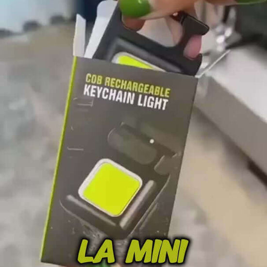 COB rechargeable keychain light in packaging held by a hand, showcasing its compact design and bright color.
