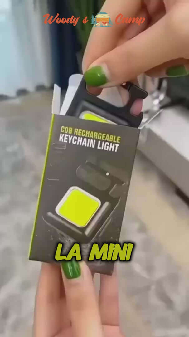 COB rechargeable keychain light in packaging held by a hand, showcasing its compact design and bright color.