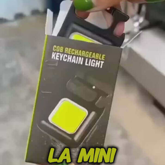 COB rechargeable keychain light in packaging held by a hand, showcasing its compact design and bright color.